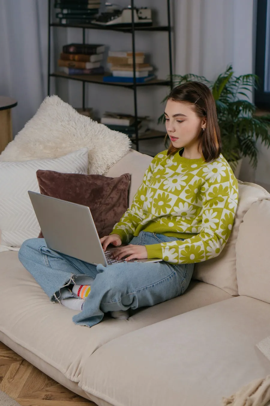 A person sitting on a sofa at home using a laptop