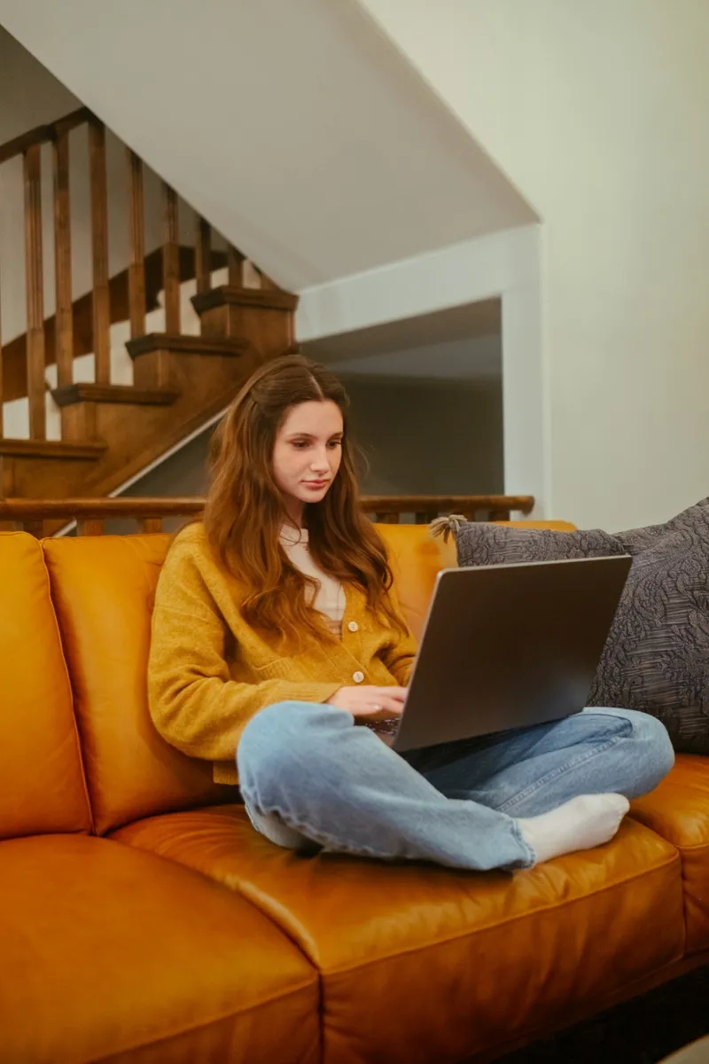 A person sitting on a sofa at home using a laptop