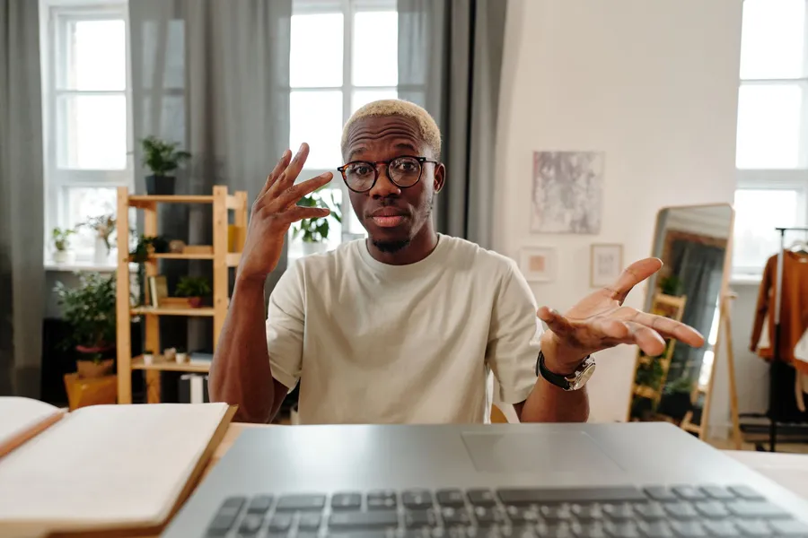 A man talking and gesturing during a laptop video call at home